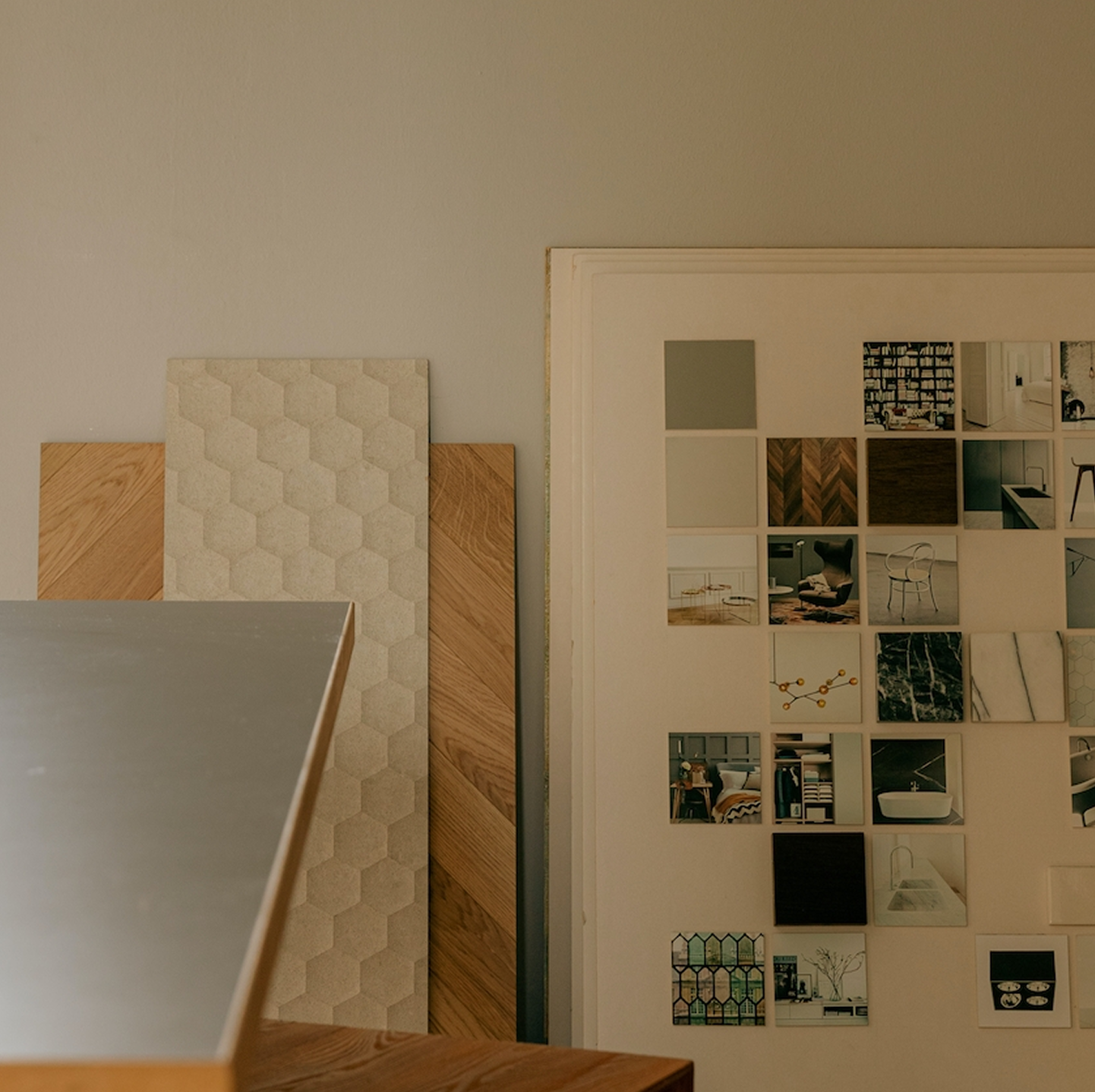 Collage of small photographs in a frame on a wall next to textured wall panels.
