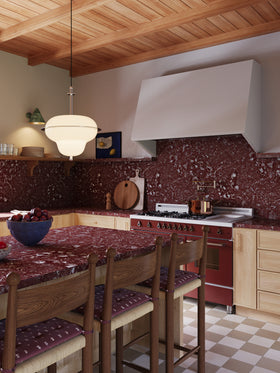 A modern kitchen featuring Isla Porter's Finn cabinets and Jove shelf in East Oak stain, Kipp range hood in "Coconuts" paint color, Burgundy Calcutta Marble countertops, brass hardware, and checkered floor tiles.